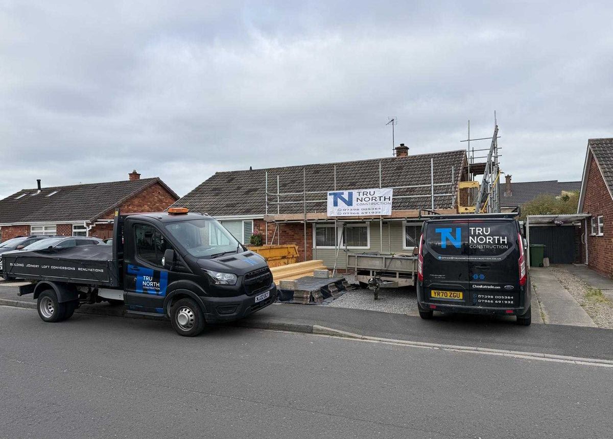 Tru North Construction vans and site banner outside a bungalow with scaffold up