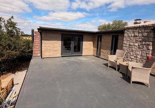 Stone extension with a flat roof terrace and french doors